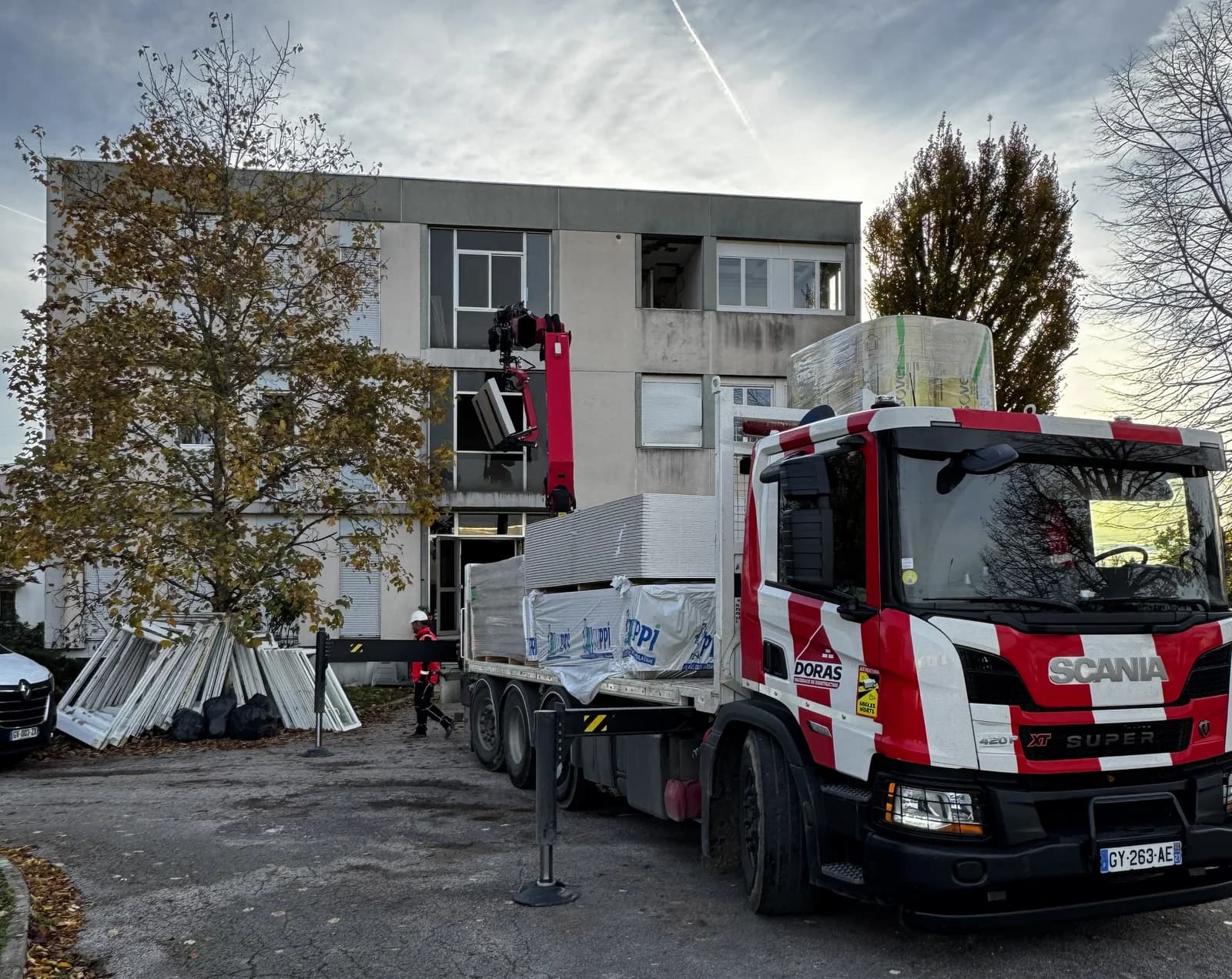 Livraison de matériaux par camion-grue devant un immeuble en cours de rénovation